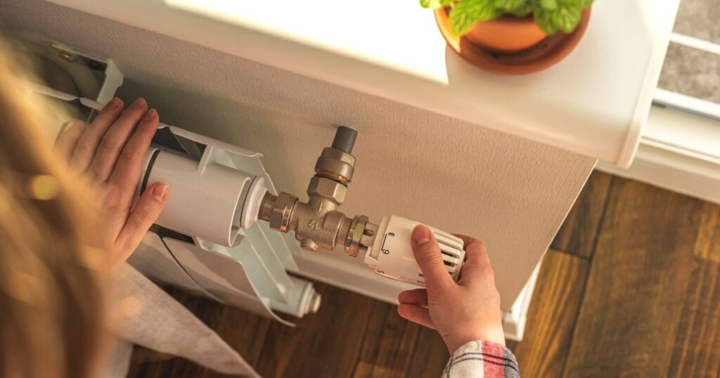 0_Woman-adjusting-the-temperature-on-valve-of-a-radiator-at-home-modern-interior-background-photo.jp_.jpeg