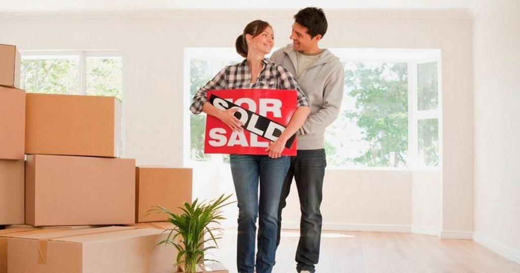 16_Couple-holding-sold-sign-for-their-new-house.jpg