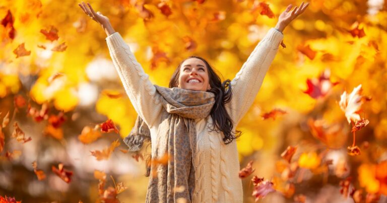 1_A-happy-young-woman-in-a-park-throws-leaves-during-an-Indian-summer-and-enjoys-autumn.jpg