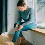 1_Woman-suffering-from-knee-pain-while-sitting-on-windowsill-at-home.jpg