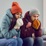 1_Young-attractive-couple-are-sitting-on-the-sofa-at-home-in-warm-clothes-and-warming-their-hands-wi.jpeg