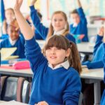 2_Elementary-school-children-wearing-blue-school-uniforms-raising-hands-in-classroom.jpg