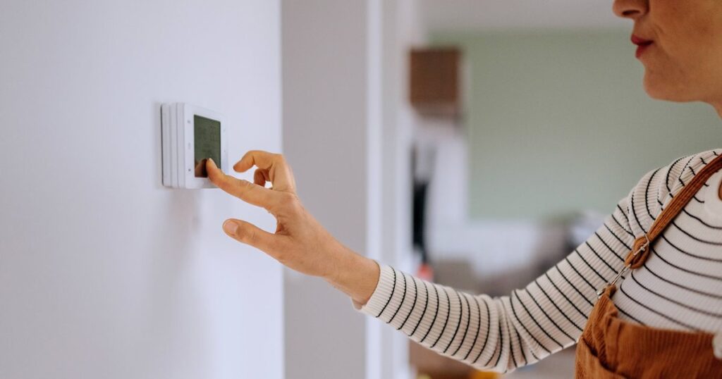 0_Casually-clothed-woman-setting-up-temperature-on-smart-thermostat-at-home.jpg