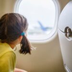 0_Little-girl-with-pigtails-sits-on-plane-staring-out-window-on-tarmac.jpg
