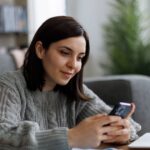 0_Smiling-woman-checking-her-phone-while-working-from-home.jpg