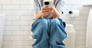 0_Woman-sitting-on-toilet-using-smartphone-in-modern-bathroom.jpg