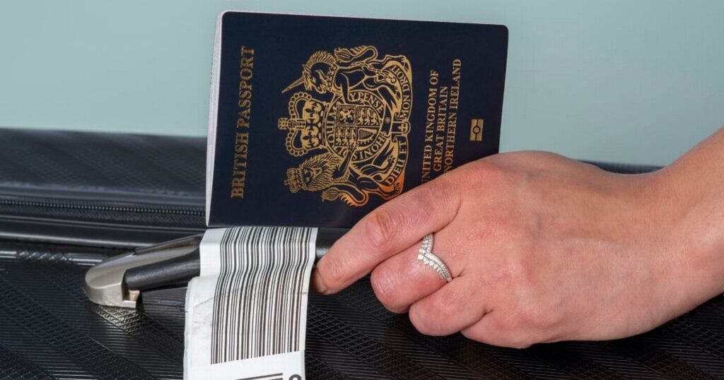 2_New-dark-blue-colored-British-passport-held-in-a-travellers-hand-with-holiday-suitcase.jpg