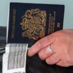 2_New-dark-blue-colored-British-passport-held-in-a-travellers-hand-with-holiday-suitcase.jpg