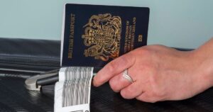 2_New-dark-blue-colored-British-passport-held-in-a-travellers-hand-with-holiday-suitcase.jpg