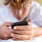 teenager-boy-using-smartphone-home-1044068096.jpg