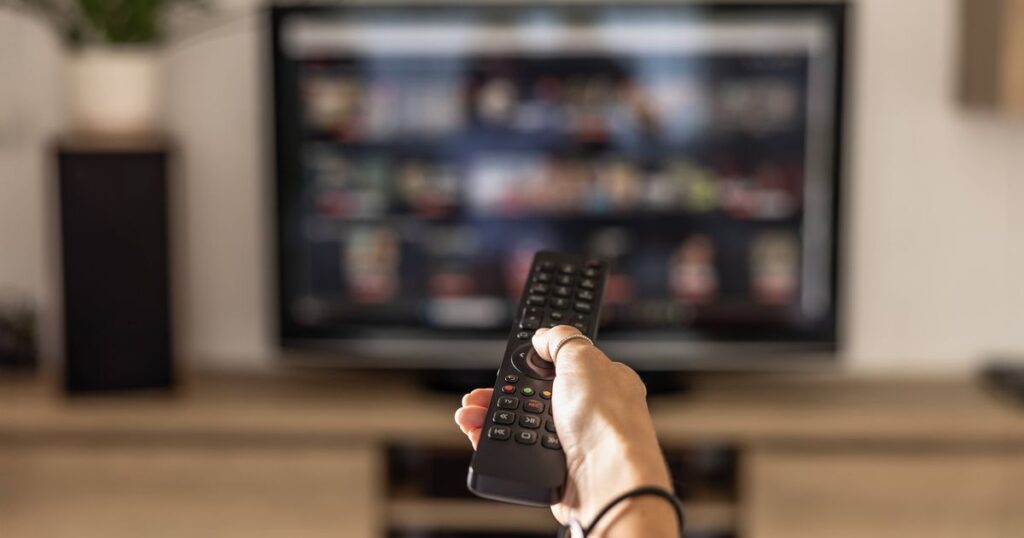 0_A-woman-is-holding-a-remote-control-of-a-smart-TV-in-his-hand-In-the-background-you-can-see-the-te.jpeg