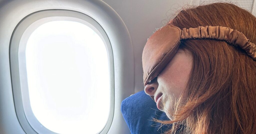 0_Close-up-image-of-redheaded-female-traveller-wearing-navy-sweatshirt-in-window-plane-seat-reclinin.jpeg