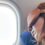 0_Close-up-image-of-redheaded-female-traveller-wearing-navy-sweatshirt-in-window-plane-seat-reclinin.jpeg