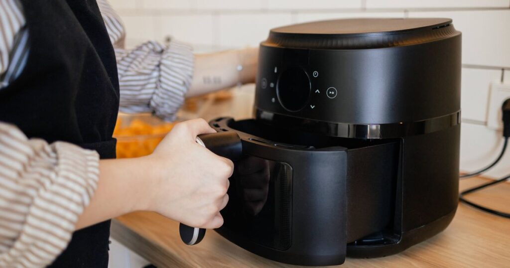 0_Close-up-view-of-a-woman-putting-a-basket-into-an-air-fryer-for-cooking.jpg