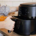 0_Close-up-view-of-a-woman-putting-a-basket-into-an-air-fryer-for-cooking.jpg
