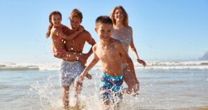 0_Family-On-Summer-Beach-Vacation-Run-Out-Of-Sea-Towards-Camera.jpg