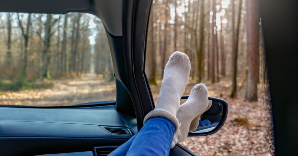 0_Feet-wearing-warm-pink-socks-and-legs-in-blue-leggings-sticking-out-of-a-car-window-in-a-forest-in.jpeg