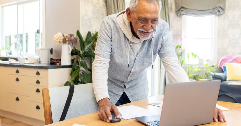 0_Man-looking-at-laptop-and-paperwork-at-kitchen-table.jpg