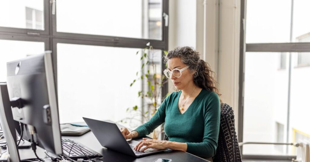 0_Mature-hispanic-woman-working-on-laptop-sitting-at-her-office-desk.jpg