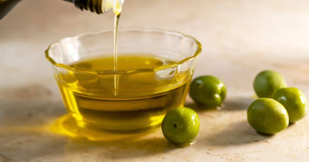 0_Olive-oil-pouring-into-small-glass-bowl-with-olives-on-table.jpg