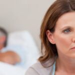 0_Sad-woman-on-bed-with-her-husband-in-the-background.jpg