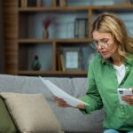0_Senior-woman-of-retirement-age-sitting-at-home-on-sofa-with-phone-and-checking-documents-bank-acco.jpeg