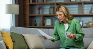 0_Senior-woman-of-retirement-age-sitting-at-home-on-sofa-with-phone-and-checking-documents-bank-acco.jpeg