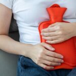0_Woman-holding-orange-hot-water-bottle-on-sofa.jpg