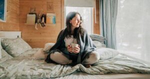 0_Woman-relaxing-in-bed-with-hot-drink-enjoying-cozy-cabin-atmosphere.jpg