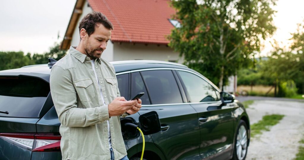 2_Man-charging-electric-car-in-front-of-house-holding-smartphone-EV-charging-app-Electric-vehicle-wi.jpeg