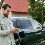 2_Man-charging-electric-car-in-front-of-house-holding-smartphone-EV-charging-app-Electric-vehicle-wi.jpeg