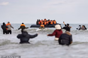 95665549-15469819-Migrants_wave_to_a_smuggler_s_boat_in_an_attempt_to_cross_the_En-a-1_1768559773695.avif