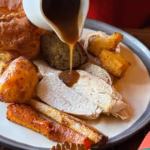 0_Full-frame-image-of-unrecognisable-woman-pouring-jug-of-gravy-over-white-plate-containing-Christma.avif
